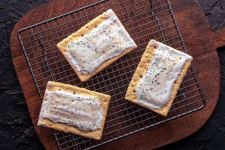 Pop tarts on a baking rack. Poptart toaster pastry with icing on a wooden cutting board, overhead flat lay shotの写真素材