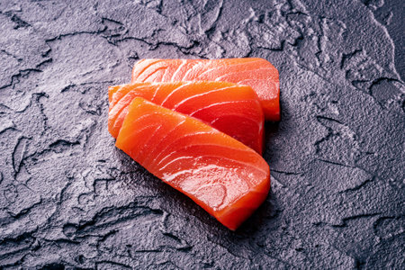 Salmon sashimi slices on a black slate background, gourmet sushi