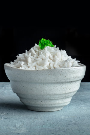 White rice, cooked. A bowl of boiled long grain rice, a simple side dish, with parsley leaves, side view with copy spaceの写真素材