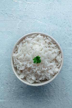 White rice, cooked. A bowl of boiled long grain rice, a simple side dish, with fresh parsley leaves, top shotの写真素材