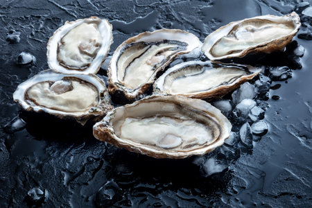 Fresh raw oysters on ice, on a black stone background, a seafood delicacy, gourmet foodの写真素材