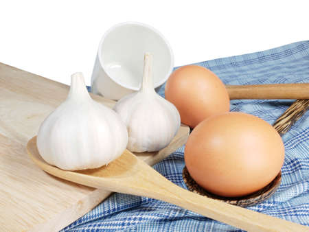 Eggs, Garlic, white cup and wooden spoon on blue fabricの写真素材