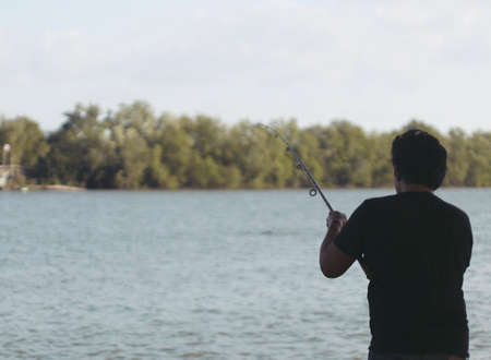 fisherman in black t-shirt fishing in river