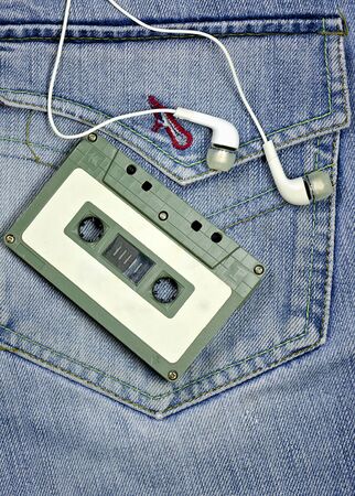 Vintage tape cassette and white earphones on jean background.の写真素材
