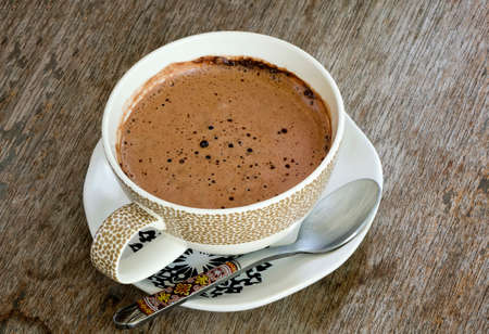 Hot chocolate in white cup on wooden background.