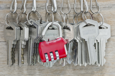 Red pad lock with bunch of old iron keys hang on the wooden wall.の写真素材