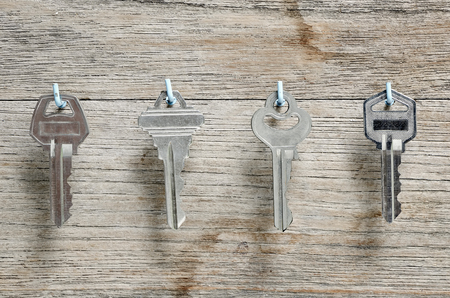 Silver keys hang on the hook on wooden wall.の写真素材