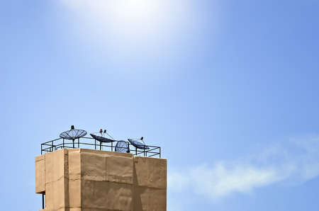 satellite dishes on top of the building under blue skyの写真素材
