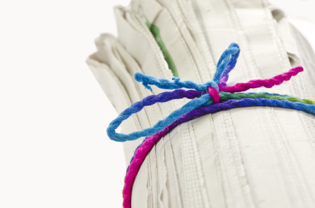 Rolled newspaper with color rope on white background.の写真素材