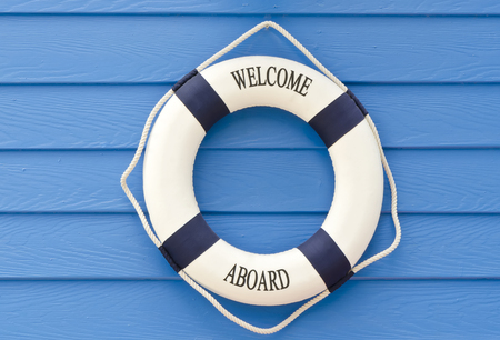 White and blue Life buoy with welcome aboard sign on blue wall