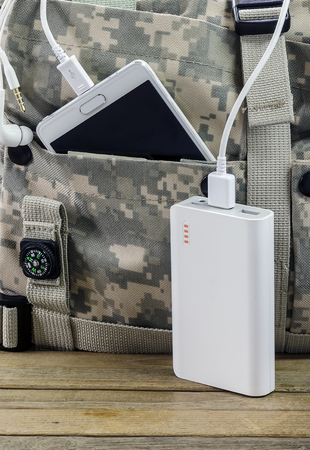 White powerbank and smartphone in the bag on wooden table.の写真素材