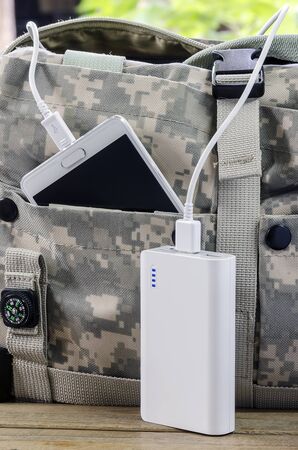 White powerbank and smartphone in the bag on wooden table.の写真素材