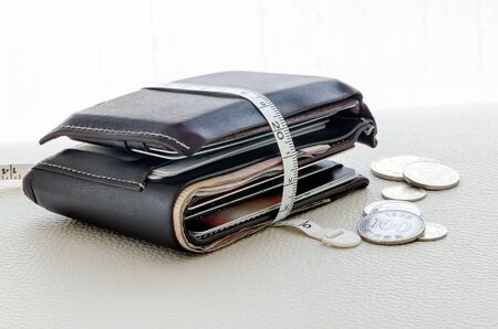 Brown wallet with white tape measure on the tableの写真素材