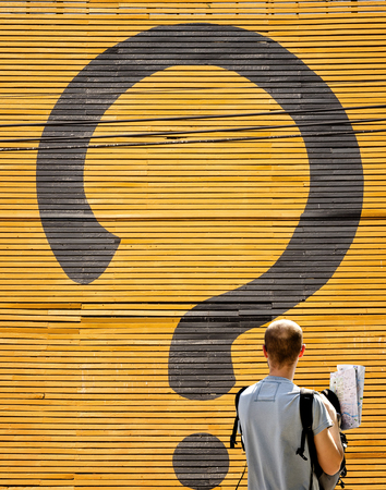 The unidentified tourist and the question mark on yellow wooden boardの写真素材