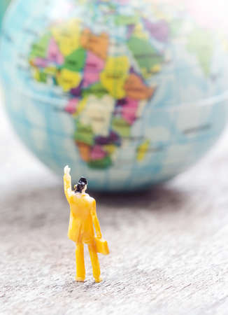 Mini model of business man waving goodbye and Simulation Globe on the wooden background,for concept background.の写真素材
