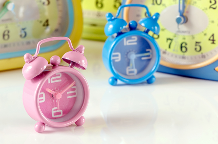 Pink alarm clock on white table with blur alarm clock background.の写真素材