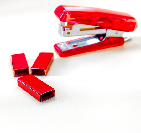 Red Stapler with red staples wires on white background,soft focus.