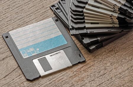 Used floppy diskettes on wooden background.