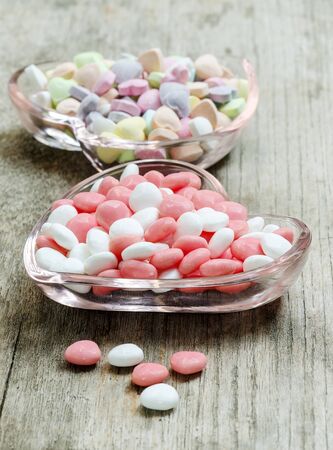 Colorful and sweet candies  in glass plate on wooden table.の写真素材