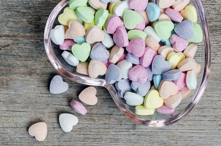 Colorful vitamin pills with heart shape in glass plate on wooden background.の写真素材