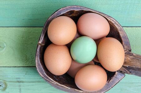 Green egg and the usual in wooden bowl on wooden background.Top view.の写真素材
