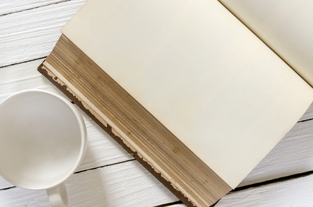 Empty white cup and  old blank book on wooden background.の写真素材