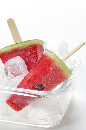Fresh watermelon with ice cream sticks in glass bowl of ice cubes.の写真素材