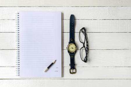 Blank note book , pencil ,watch and eyes glass on wooden background.の写真素材