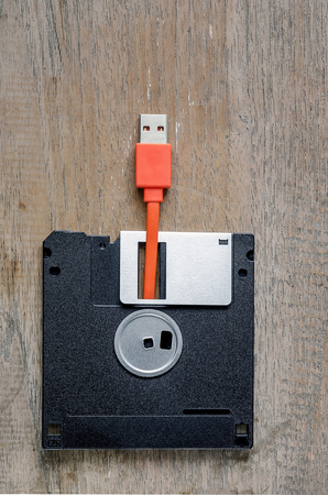 Used floppy diskettes with orange USB cable Plug on wooden background,design for technology conceptの写真素材
