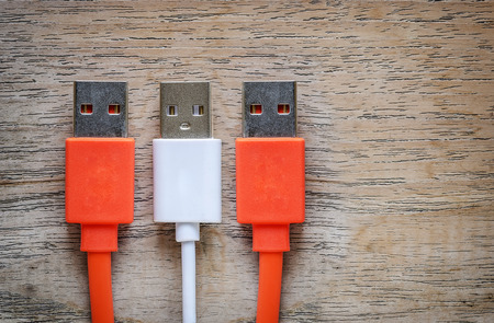 Orange and white USB cable Plug on wooden background.