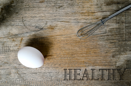 egg and Stainless Steel Egg Whisk on wooden backgroundの写真素材