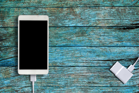 White smartphone and Phone Charger on blue wooden backgroundの写真素材