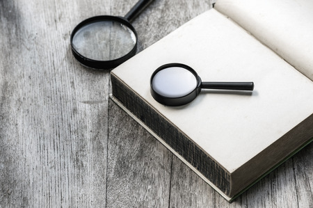 magnifier on blank notebook on a wooden background.