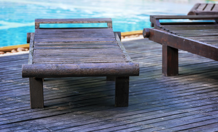 Outdoor poolside couch chairs, wooden benches beside the swimming poolの写真素材