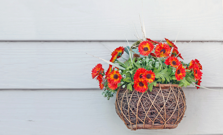 plastic flower in basket hang on white wooden wallの写真素材