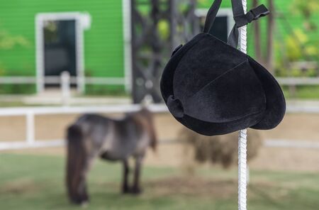 Helmet jockey hang on iron pole at  training stable