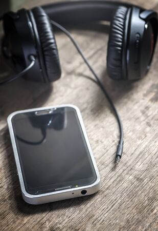unplugged earphones mini-jack smartphone connector on wooden board, shallow depth of fieldの写真素材