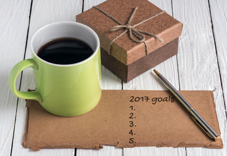 green cup of coffee,brown gift box ,pen and old paper note on white wooden background.の写真素材