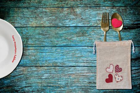 White plate and bag of spoon and fork with red heart on blue wooden background,valentine day concept.の写真素材