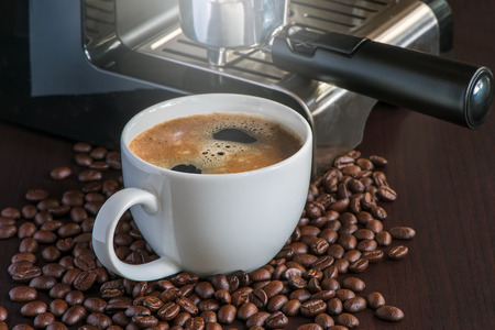 white cup of hot coffee with coffee beans on wooden tableの写真素材
