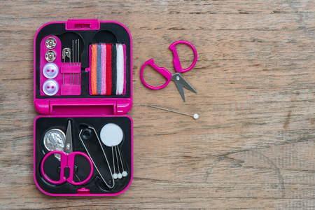 sewing kit, needles, thread in a pink box on wooden table,top viewの写真素材