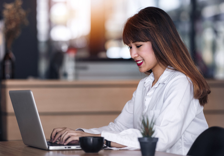 Attractive Asian businesswoman in white shirt using laptop at her deskの写真素材