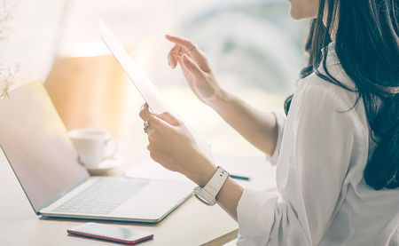 Cropped image of businesswoman holding document paper while working at officeの写真素材