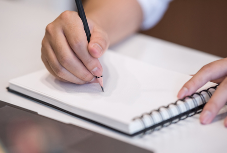 Cropped image of man writing on notebook while working at officeの写真素材