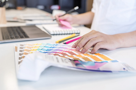 Close up view of male designer pointing on color shade and choosing color for new project at his desk in officeの写真素材