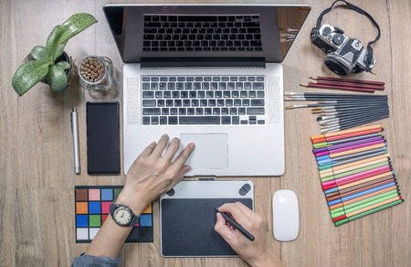 Top view of man designer using laptop computer and graphics tablet at home office. Professional occupation workplaceの写真素材