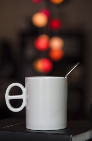 Close up white coffee cup on the book and colorful blur light bokeh in dark backgroundの写真素材
