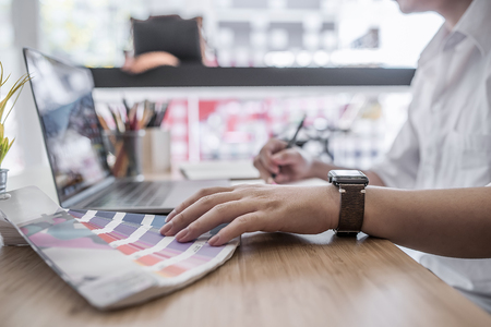 Close up view of male designer pointing on color shade swatch and choosing color for new project at his desk in officeの写真素材
