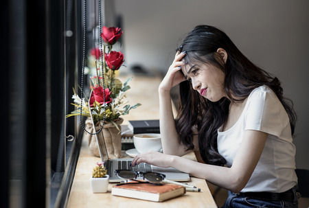 Stressed female designer sitting and using laptop at desk in modern office