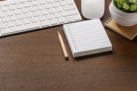 Mockup of white keyboard, mouse, to do list note, pencil and houseplant on wooden table with copy spaceの写真素材